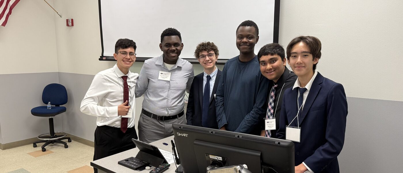 Six members of the project team standing together behind a presentation
                    console at the research symposium.